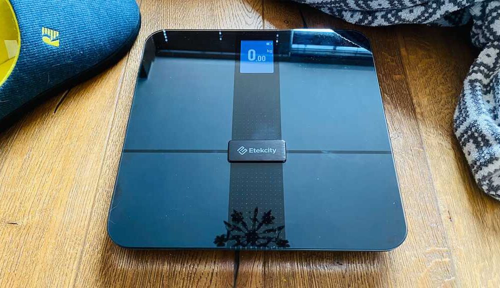 Etekcity smart scale on a floor next to a towel and slippers