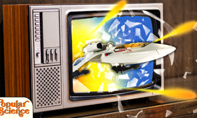 a spaceships breaks through an old tv with glass flying