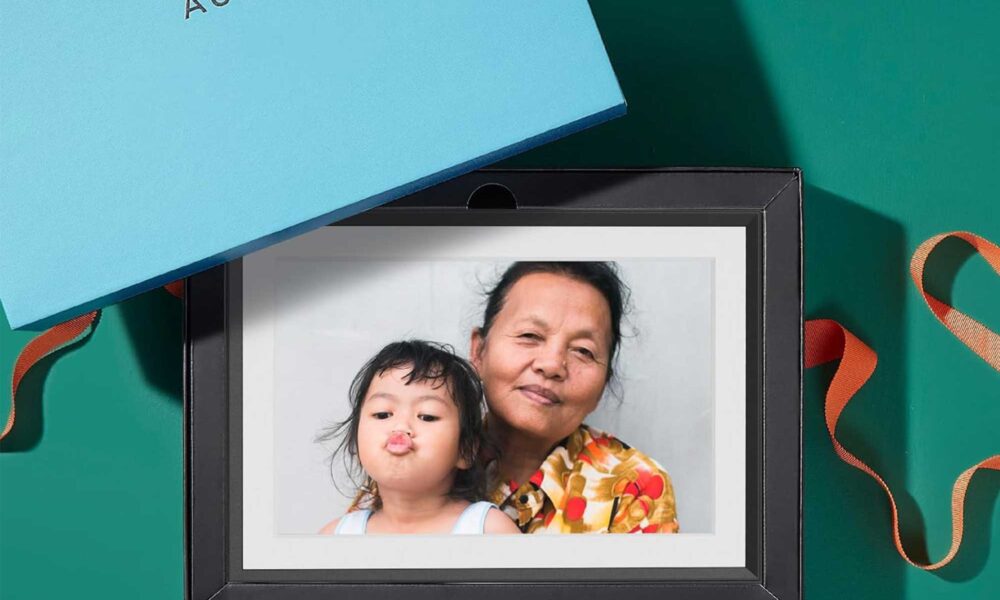 An Aura picture frame near a gift box with a grandma and child displayed on it.