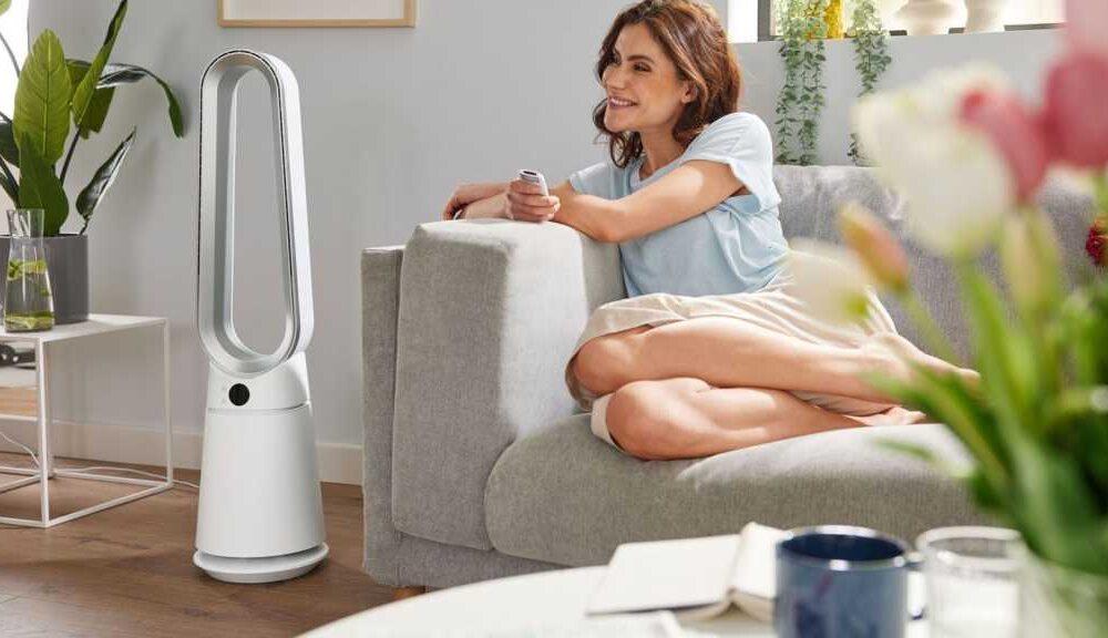 Lidl Silvercrest fan in white, next to a woman sitting on a sofa