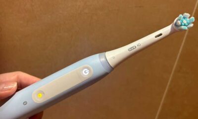 A hand holding an Oral-B brush with a glowing mode button