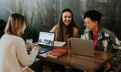 Three women with laptops laughing.