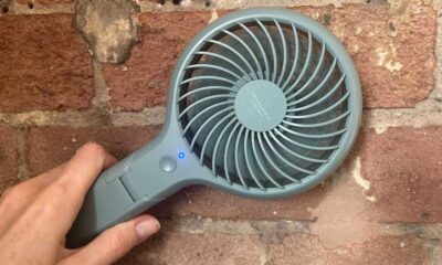 John Lewis Anyday fan in a hand, held in front of a brick wall